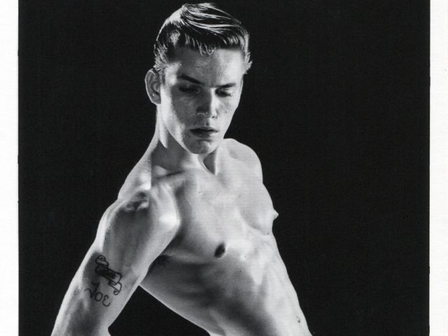 This is a black and white photograph by Bruce of Los Angeles of Joe Dallesandro standing naked posing with his arms behind his back.
