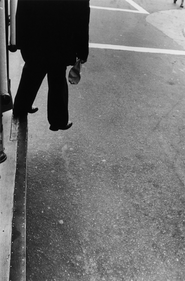 This is a photograph by Dorothea Lange of a man stepping off the street in San Francisco.