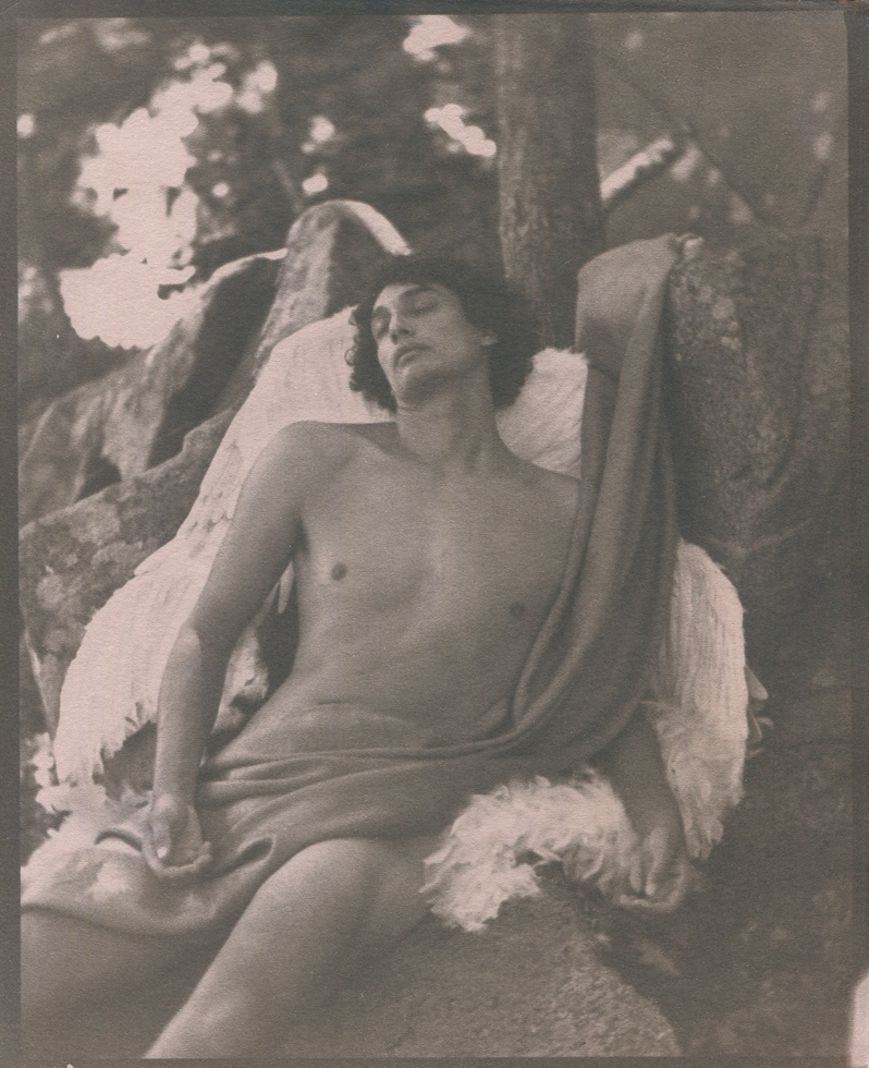 This is a photograph by Curtice Taylor titled "Fallen Angel" of a nude man covered in a cloth with angel wings.