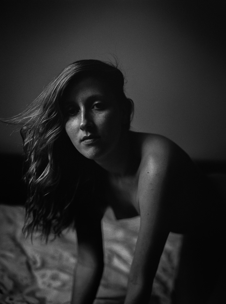 This is a black and white photograph of a woman in a bed.