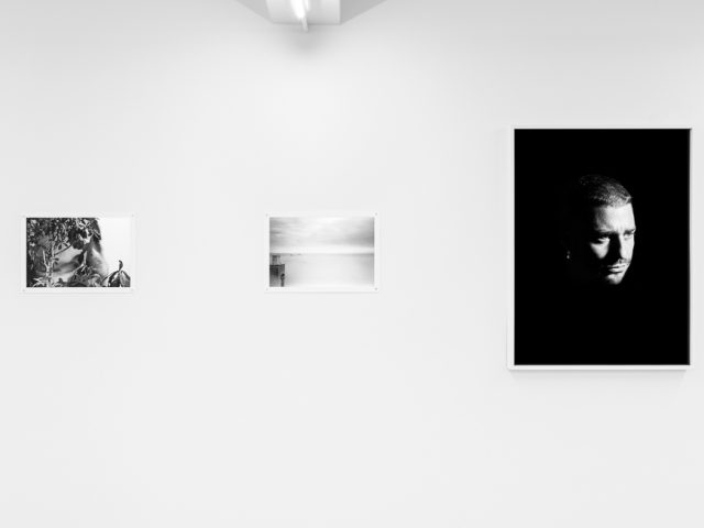 This is a photograph of a white-walled art gallery with black and white photographs on the wall.