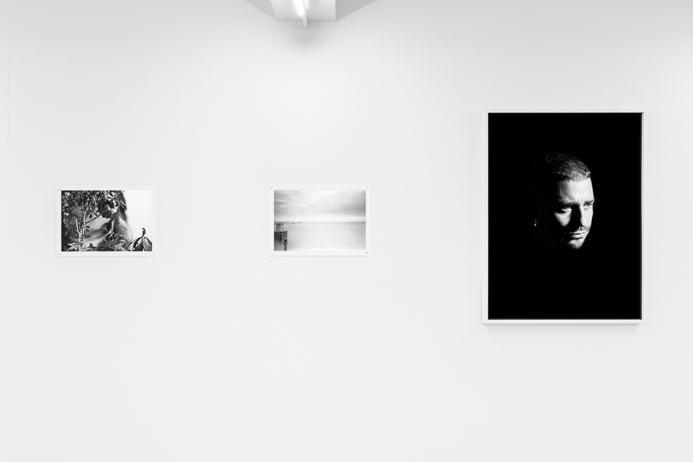 This is a photograph of a white-walled art gallery with black and white photographs on the wall.