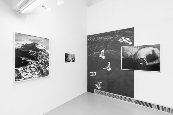 This is a photograph of a white-walled art gallery with black and white photographs on the wall.