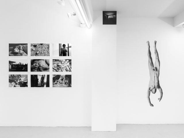 This is a photograph of a white-walled art gallery with black and white photographs on the wall.