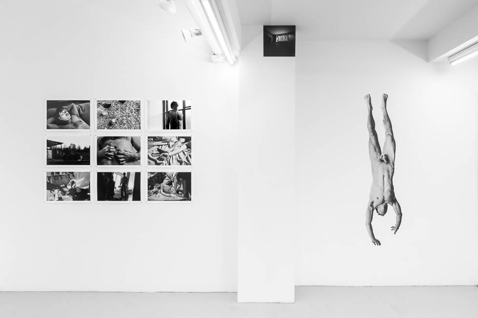 This is a photograph of a white-walled art gallery with black and white photographs on the wall.