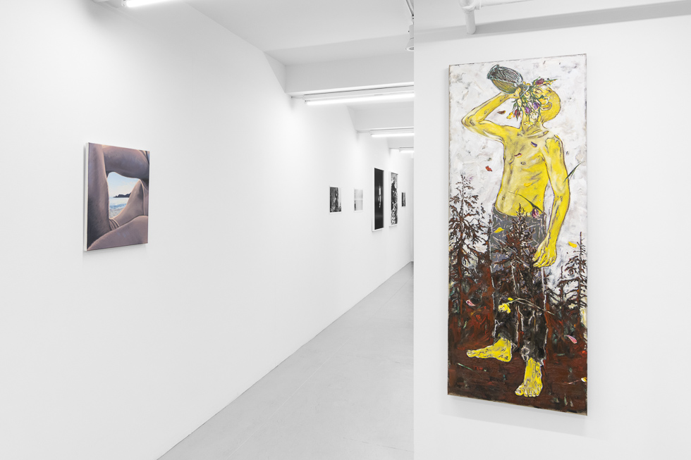 This is a photograph of a white-walled art gallery with colorful contemporary figurative paintings.