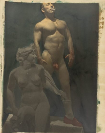 This is a photograph of a nude man standing beside a classical marble statue of a woman.