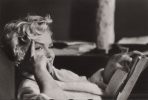 This is a black and white photograph of Marilyn Monroe sitting with her right hand on her face.