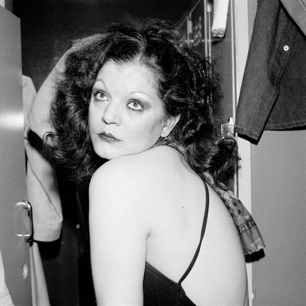 This is a black and white photograph of a woman with dark hair in a black top.
