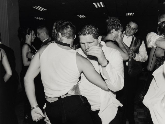 This is a black and white photograph taken with flash at a school dance of various figures dancing.