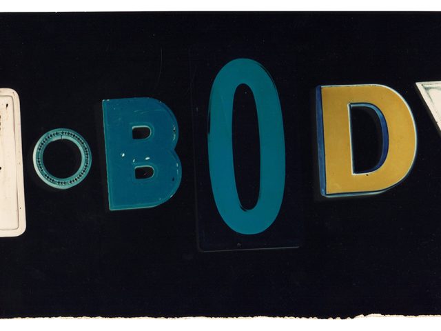 This is a color photograph of blue, yellow, and white letters on a black background spelling the word "nobody."