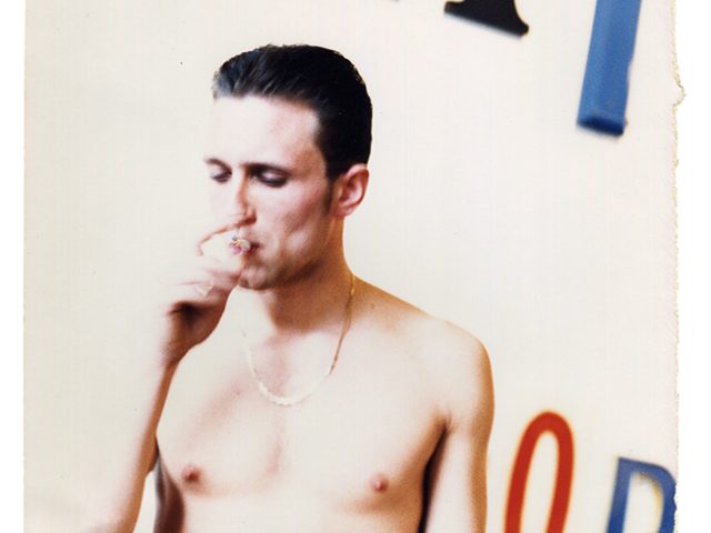 This is a photograph of a nude man smoking a cigarette.