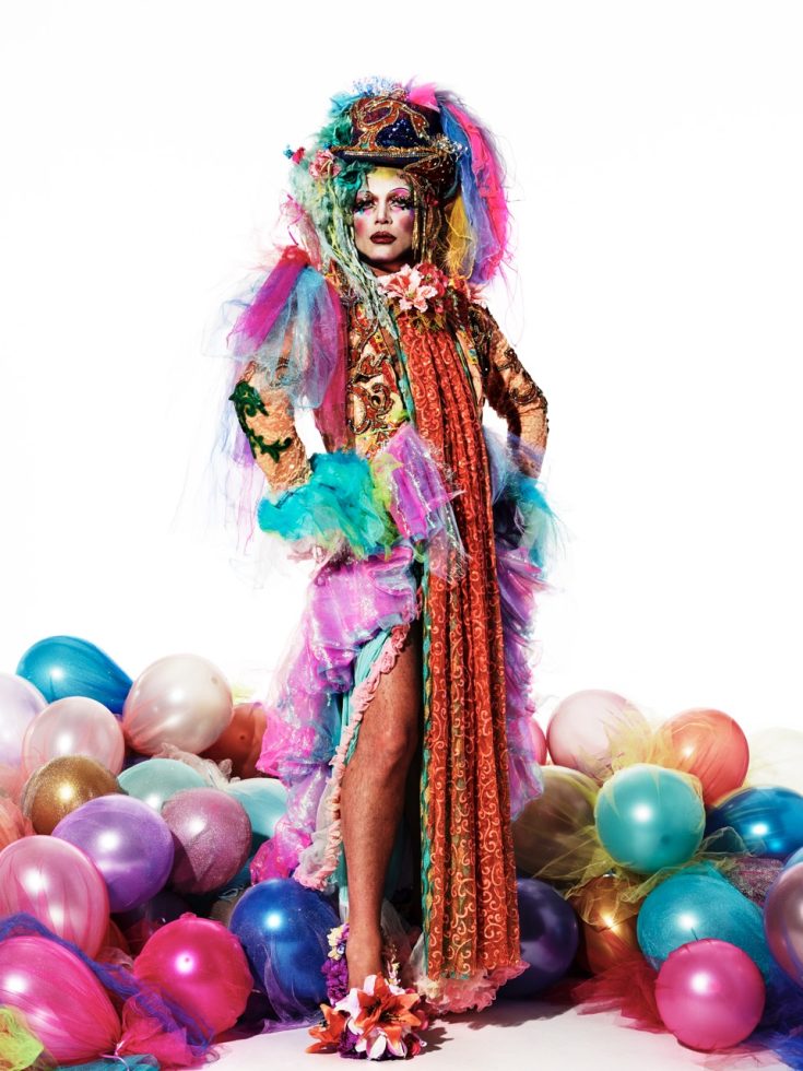 This is a photograph of a person wearing an elaborate costume in front of a white paper backdrop.