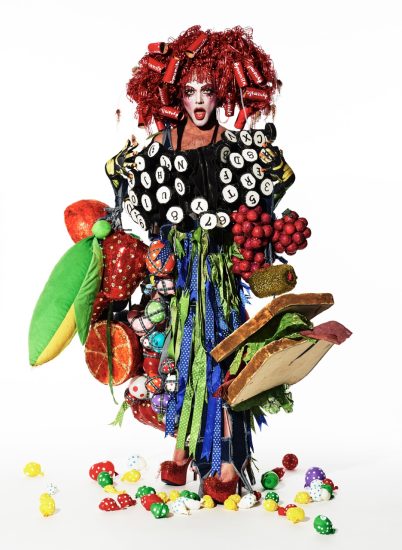 This is a photograph of a person in an elaborate costume standing in front of a white backdrop.