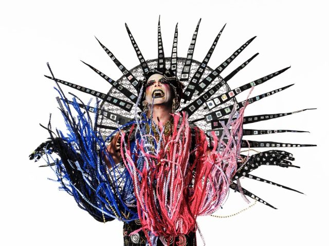 This is a photograph of a person in an elaborate costume in front of a white background.