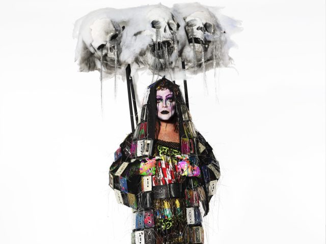 Click for sizes / editions / prices. This is a photograph of a person in a colorful costume against a white backdrop.