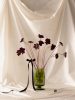 This is a color photograph of a floral still life in a green vase with a black bow and a black die.