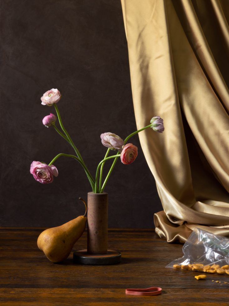 This is a photograph of goldfish, pears, ranunculus flowers, a golden sheet, and a rubber band.