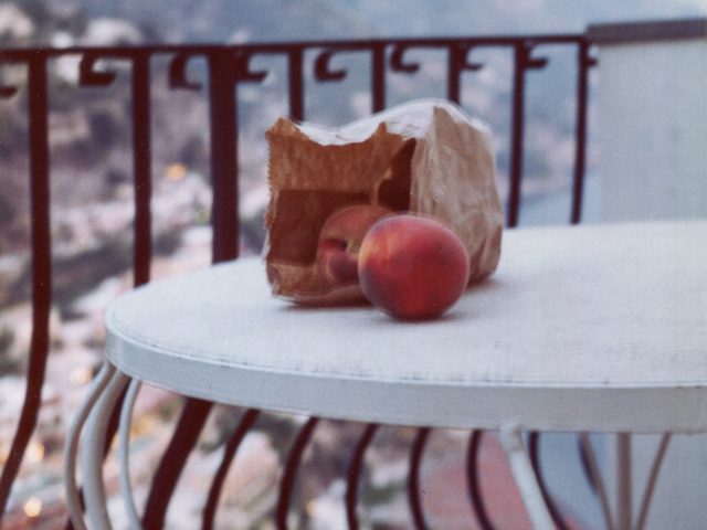 This is a photograph of a peach and a brown paper bag on a terrace in positano.