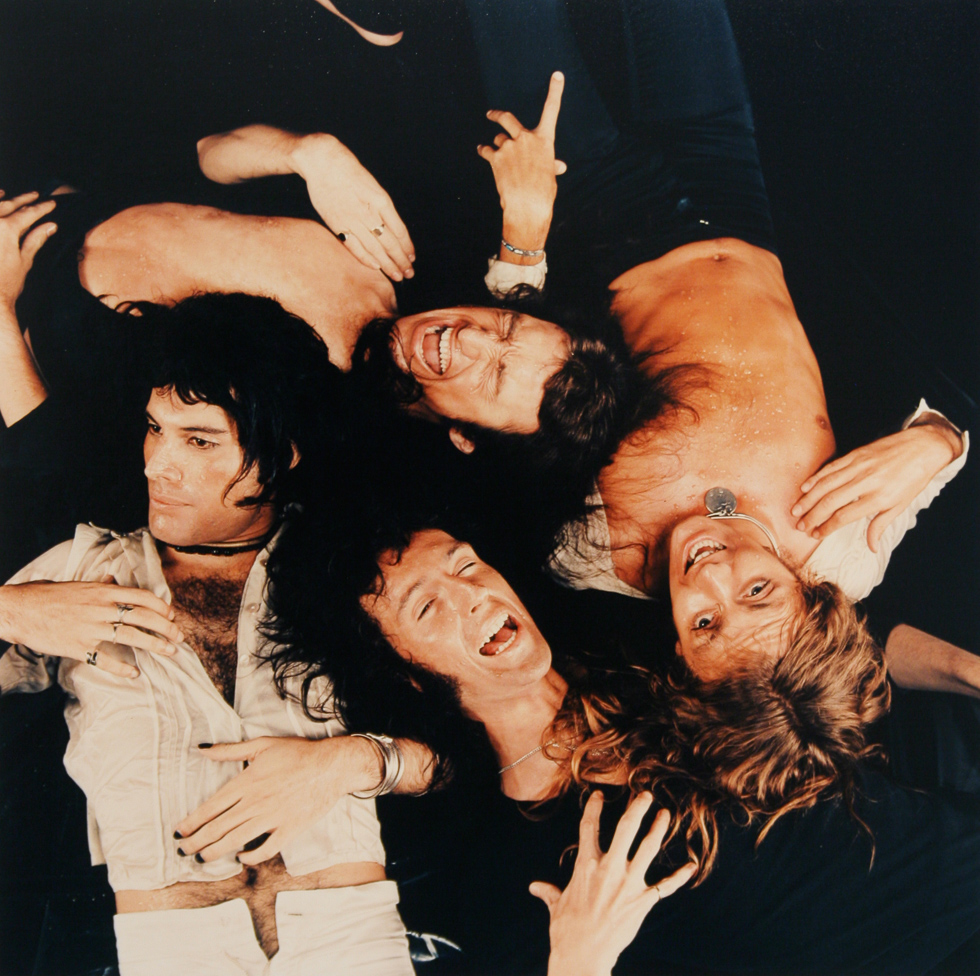 This is a photograph of the band Queen lying on the ground taken from above with their shirts open.