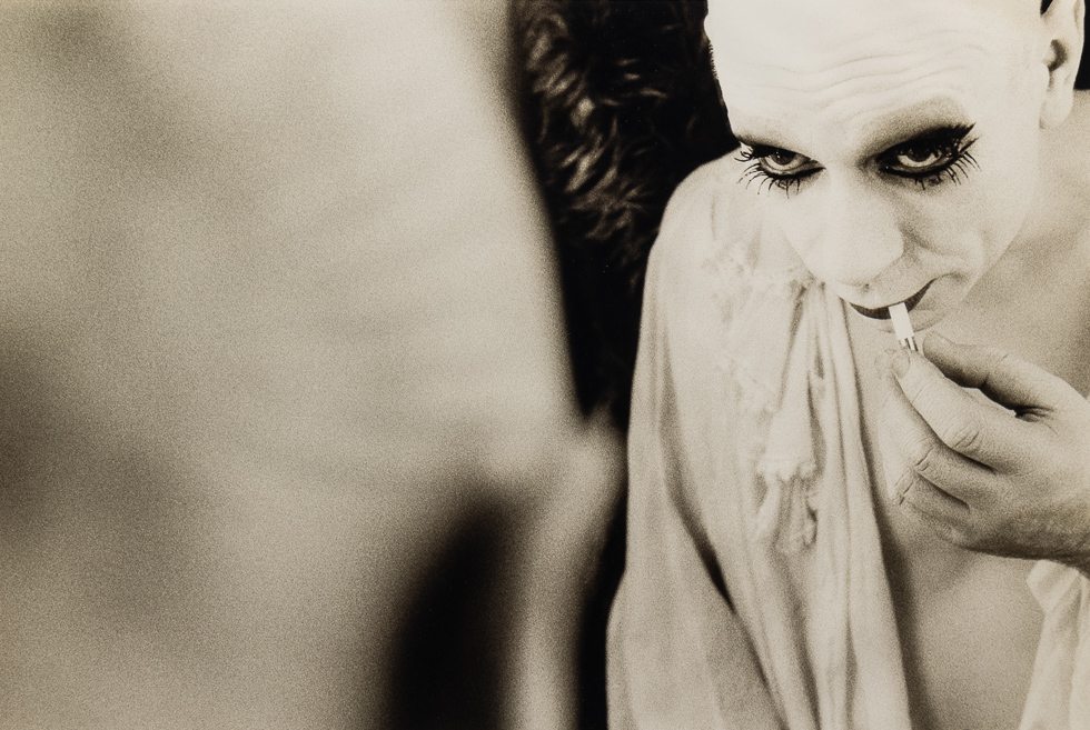 This is a black and white photograph of a French Mime Applying Make Up in a Mirror.