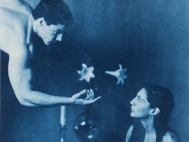 This is a cyanotype of a nude man gesturing towards a seated nude woman.