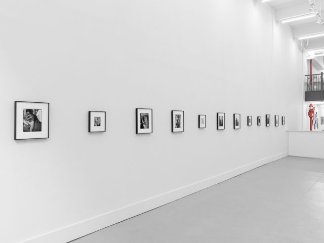 This is a photograph of black and white framed images on display in a minimalistic gallery setting.