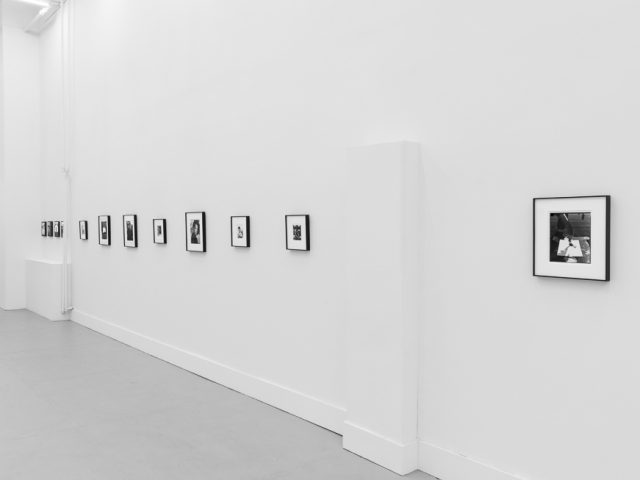 This is a photograph of black and white framed images on display in a minimalistic gallery setting.