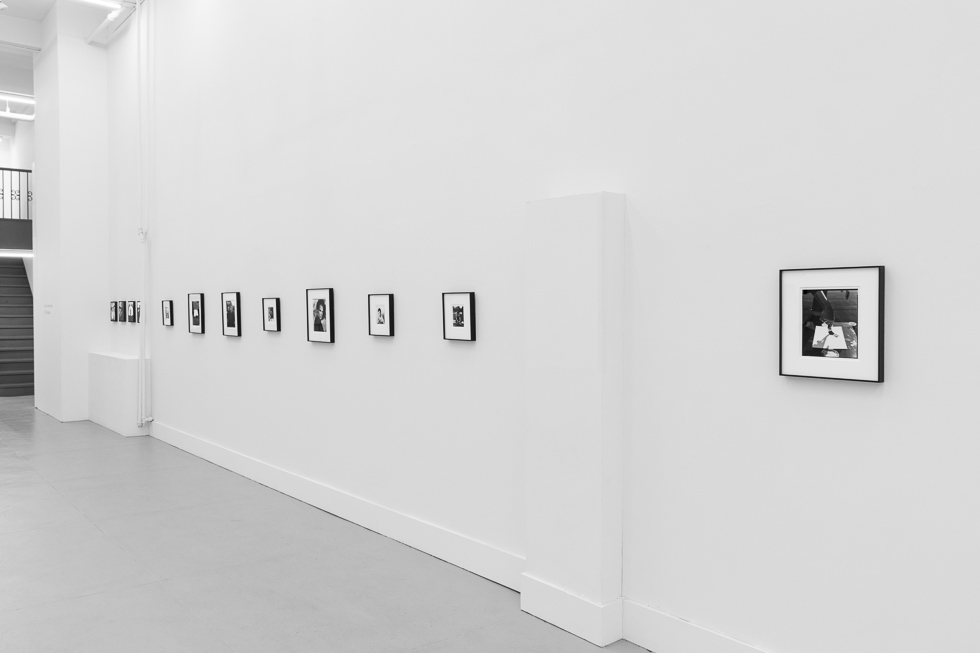 This is a photograph of black and white framed images on display in a minimalistic gallery setting.