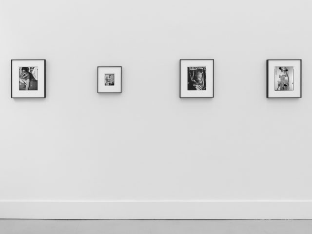 This is a photograph of black and white framed images on display in a minimalistic gallery setting.