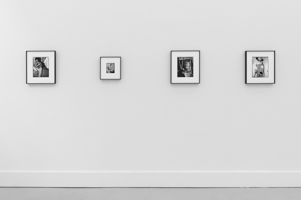 This is a photograph of black and white framed images on display in a minimalistic gallery setting.