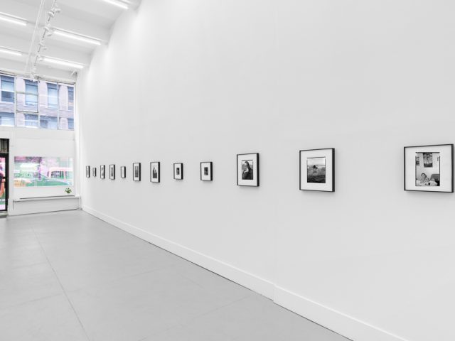 This is a photograph of black and white framed images on display in a minimalistic gallery setting.