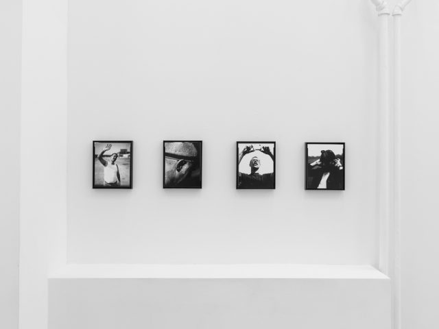 This is a photograph of black and white framed images on display in a minimalistic gallery setting.