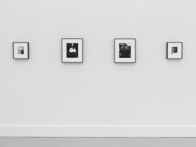 This is a photograph of black and white framed images on display in a minimalistic gallery setting.