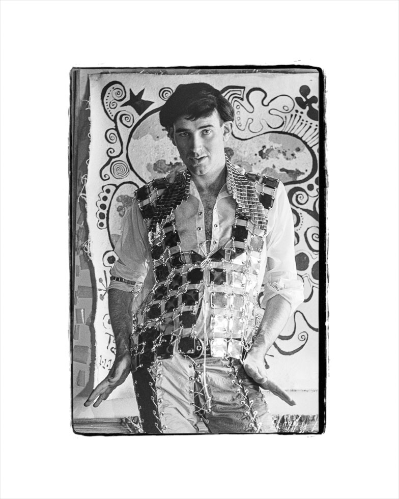 This is a black-and-white photograph of a man in an eccentric shirt posing for a picture.