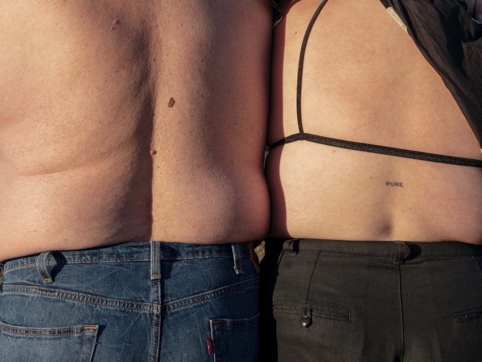 This is a color photograph of two people's backs facing the camera.