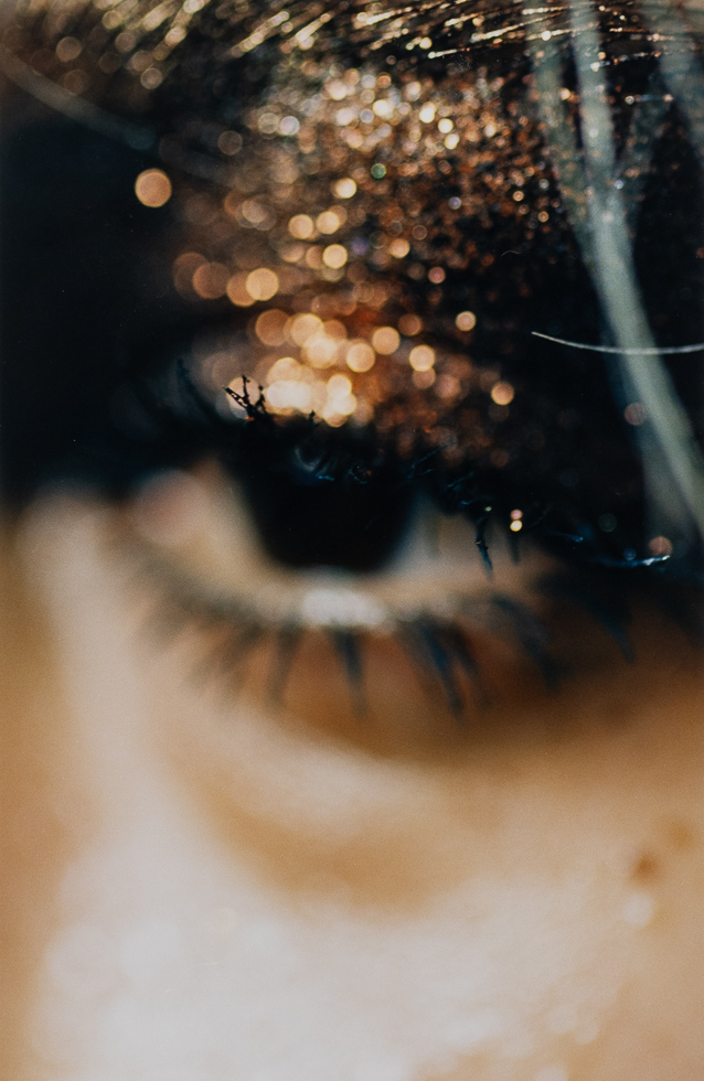 This is a close up blurry photograph of a woman's eye with glittery brown makeup.
