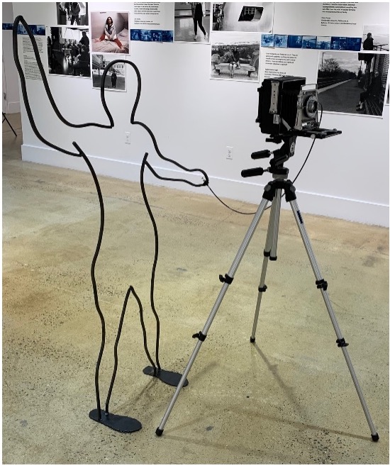This is a photograph of a metal sculpture next to a camera on a tripod.