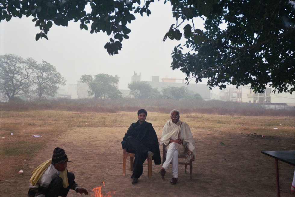 This is a photograph of two men sitting in a field.