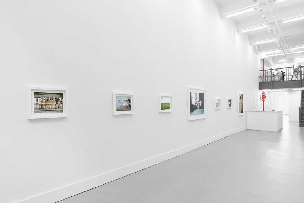This is a photograph of a photography gallery with nude pictures on display on white walls.