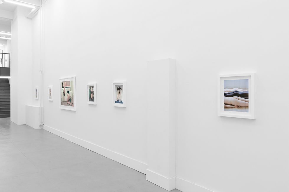 This is a photograph of a photography gallery with nude pictures on display on white walls.