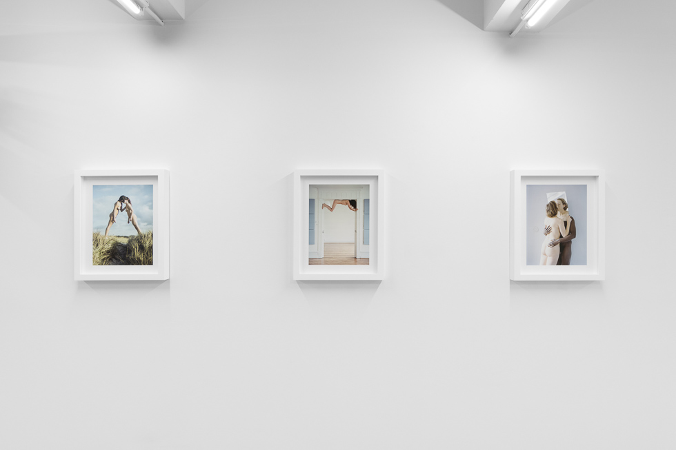 This is a photograph of a photography gallery with nude pictures on display on white walls.