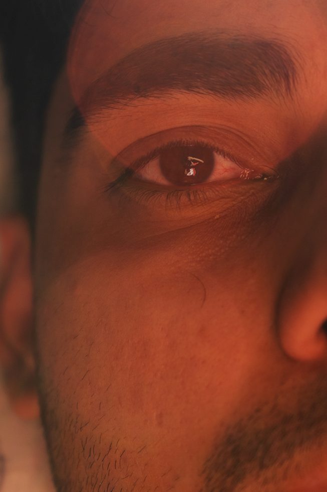 This is a photograph of one half of a man's face in red lighting.