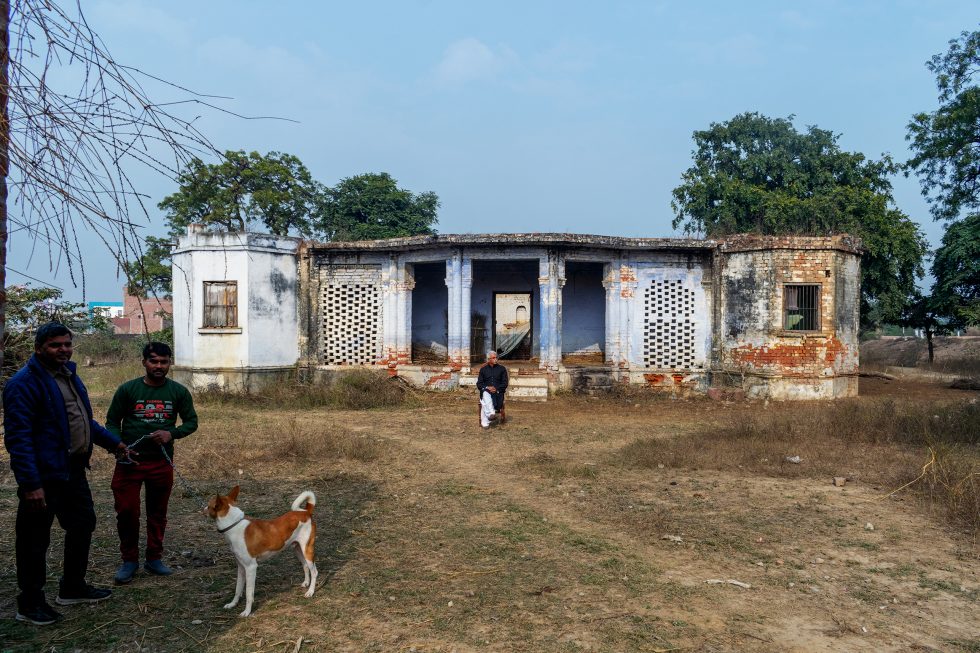 This is a color photograph of a decrepit building in a field.