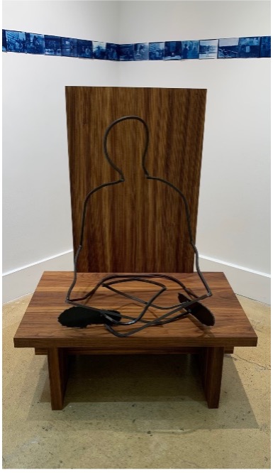 This is a wooden chair with a metal figure sitting in it.
