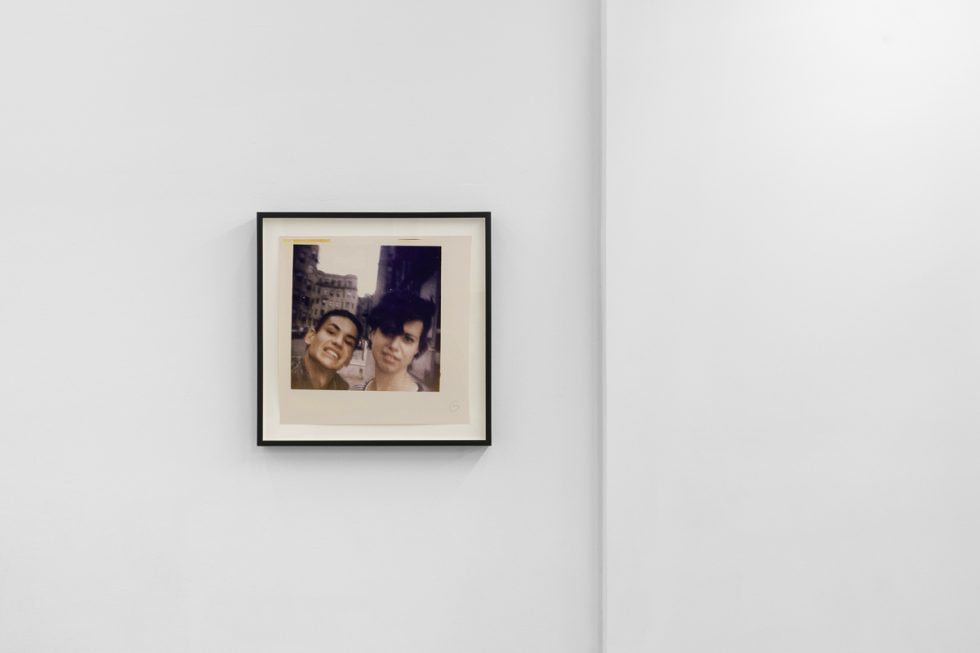 This is a photograph of a series of pictures hanging on the wall of a white, stark, gallery space.