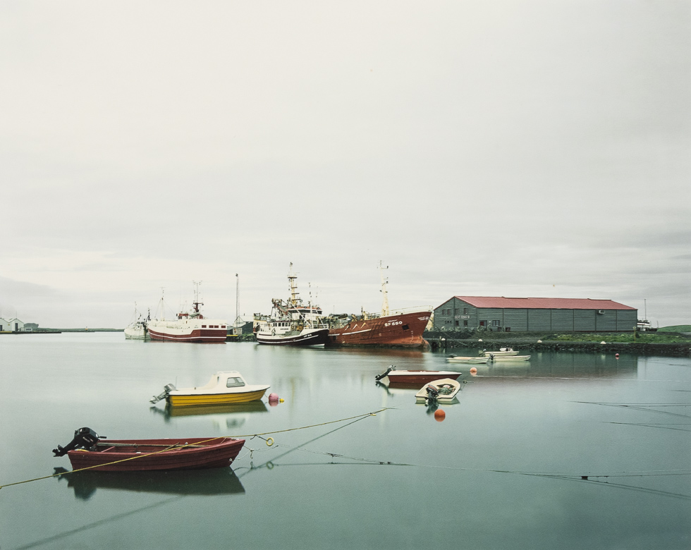 Boats rest on still and peaceful harbor water.