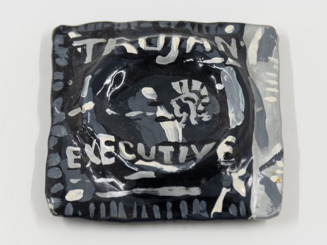 A square, hand-painted paperweight featuring the word "TROJAN," a helmet logo, and "EXECUTIVE" text. Dark background with white and gray accents.