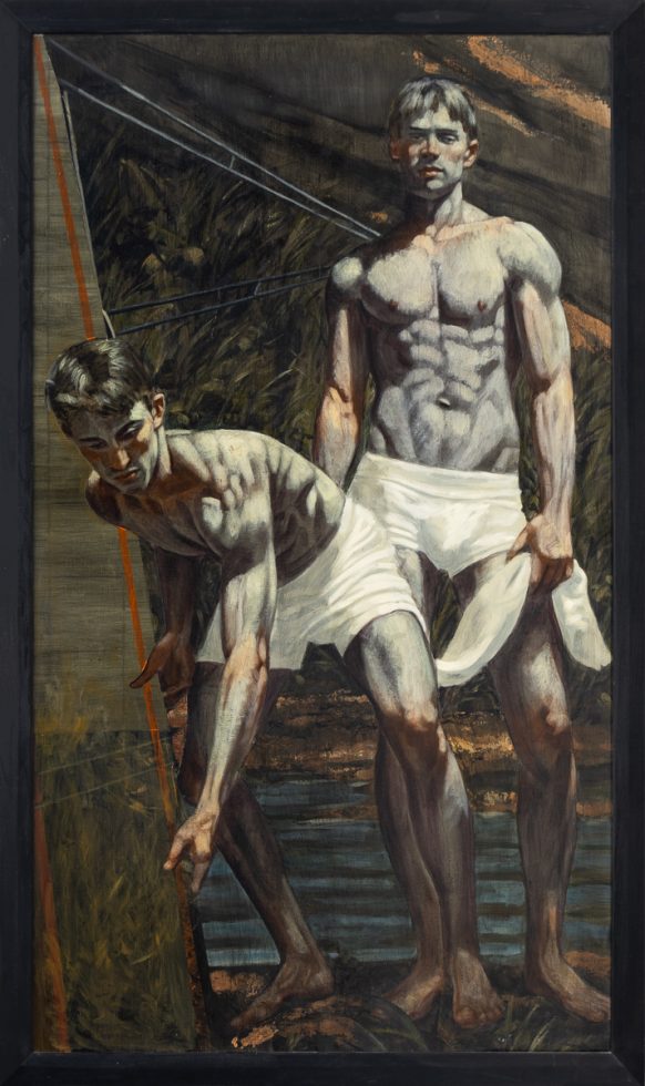Two men with a surfboard stand on a shoreline.