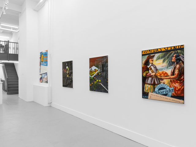A modern art gallery displays a vintage orange advertisement alongside other artworks, possibly with a Florida theme.